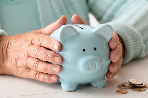 Foto: türkises Sparschwein zwischen alten Händen